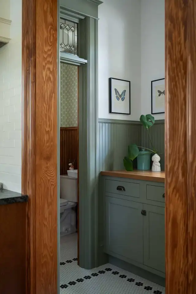Green painted pantry in a 1902 Northwest Portland home with glass-front cabinets and black-and-white hexagon floor tile