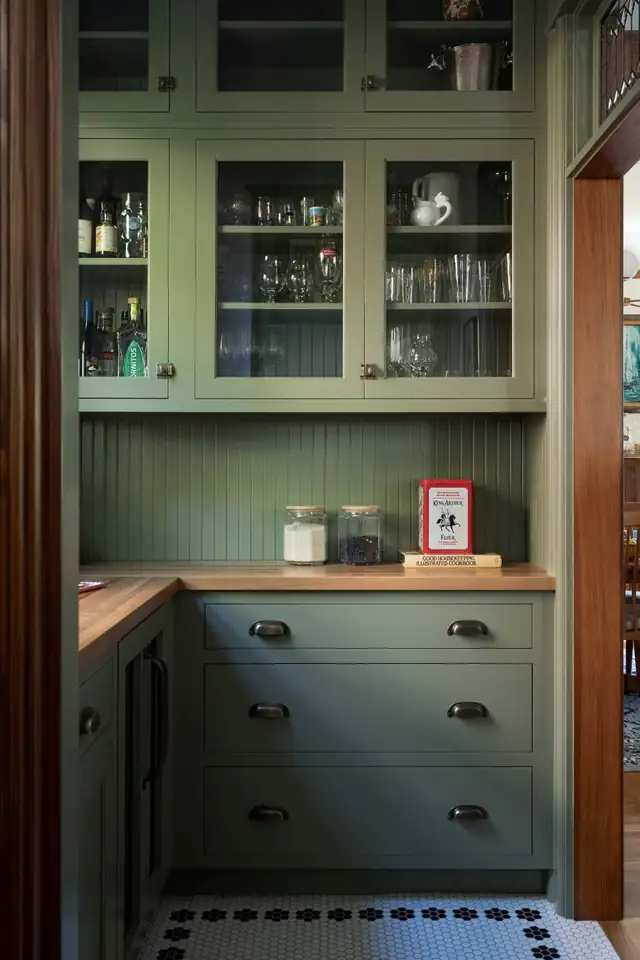 Green pantry in a 1902 Northwest Portland home with glass-front upper cabinets, butcher block counters and hexagon floor tile