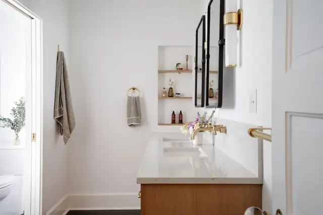 Primary bathroom in a 1910 Alameda home with a white quartz vanity on a wood base, brass fixtures and a built-in wall niche