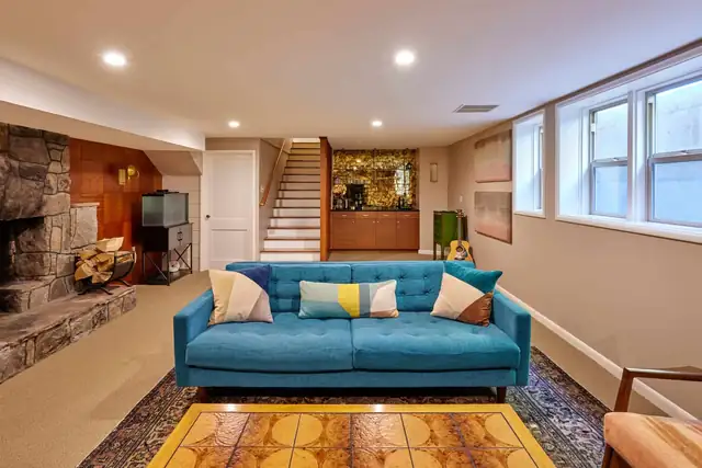 1950 Laurelhurst Rambler basement remodel with stone fireplace wall, teal sofa, recessed lights and daylight windows