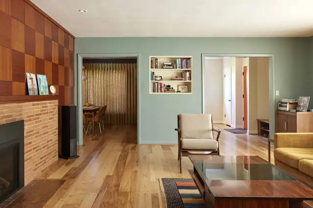 1950 Laurelhurst rambler living room with a brick fireplace, wood paneling, a built-in bookcase and sage green walls